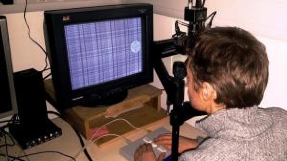 A person sitting at a desk with a screen performing a task for assessing memory in humans