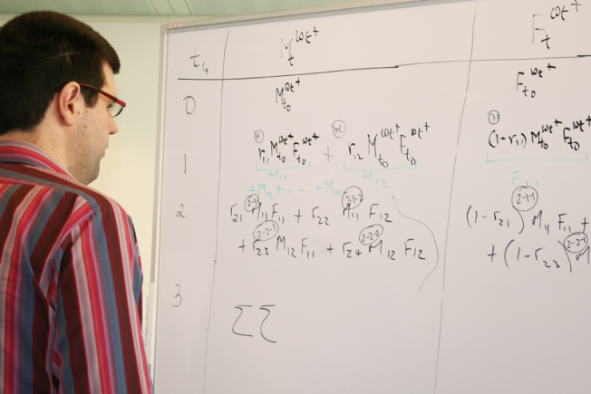 Mathematician staring at maths problems on a whiteboard