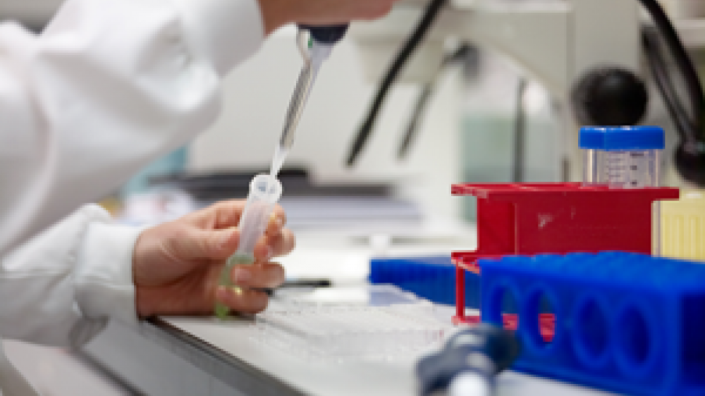 A laboratory technician with a sample tube injecting fluid into it