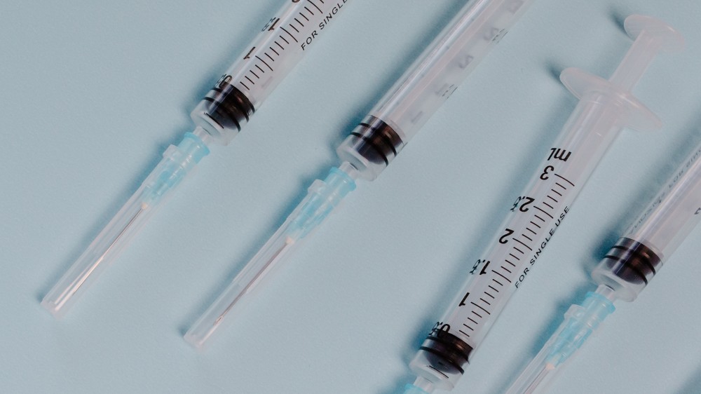 Five needles with empty syringes on a pale blue background