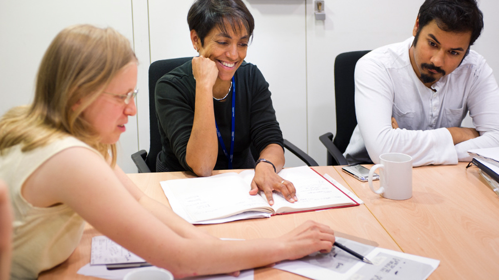 Three researchers sitting down at a table reviewing paperwork