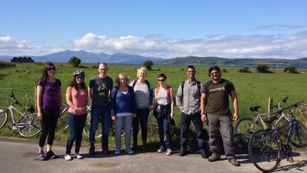 A group of researchers stand smiling on a sunny day after having paused on a bike ride.