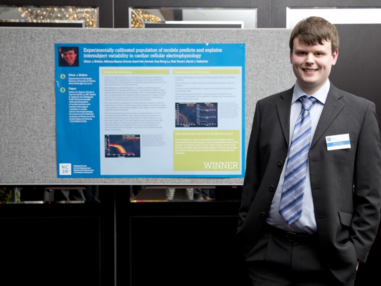 2014 3Rs prize winner Mr Oliver Britton standing in front of a poster presenting his work.