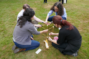 Four students sitting on the grass building a cube