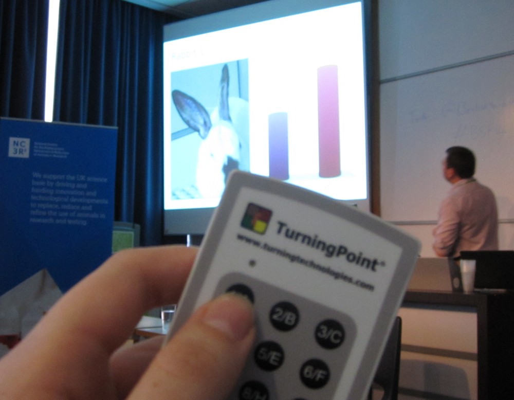 A presentation being given and a remote control device is being held up to the camera at the British Science Festival