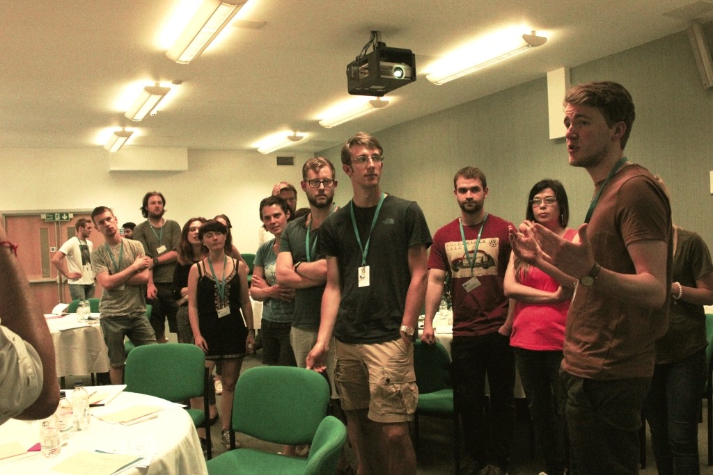 A group of students in a large room listening to there colleague 