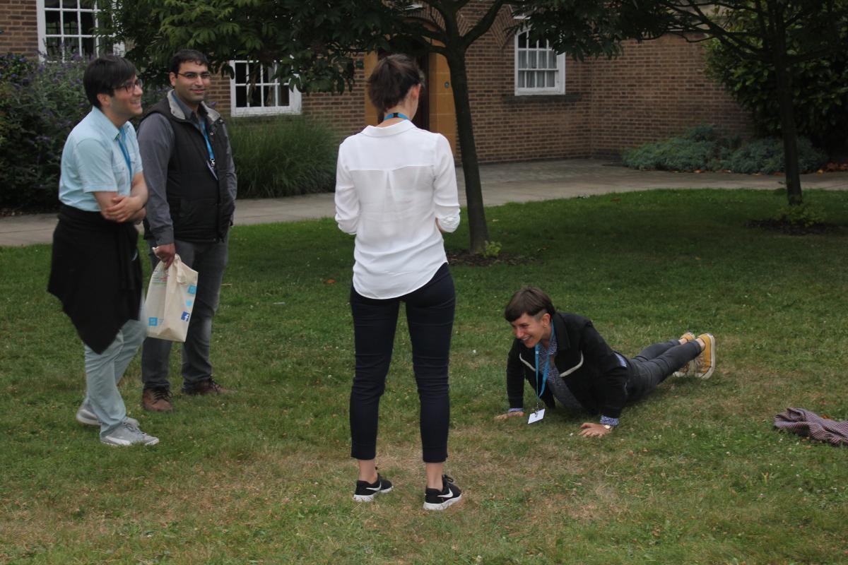 A student is doing press ups while three students stand looking at him 