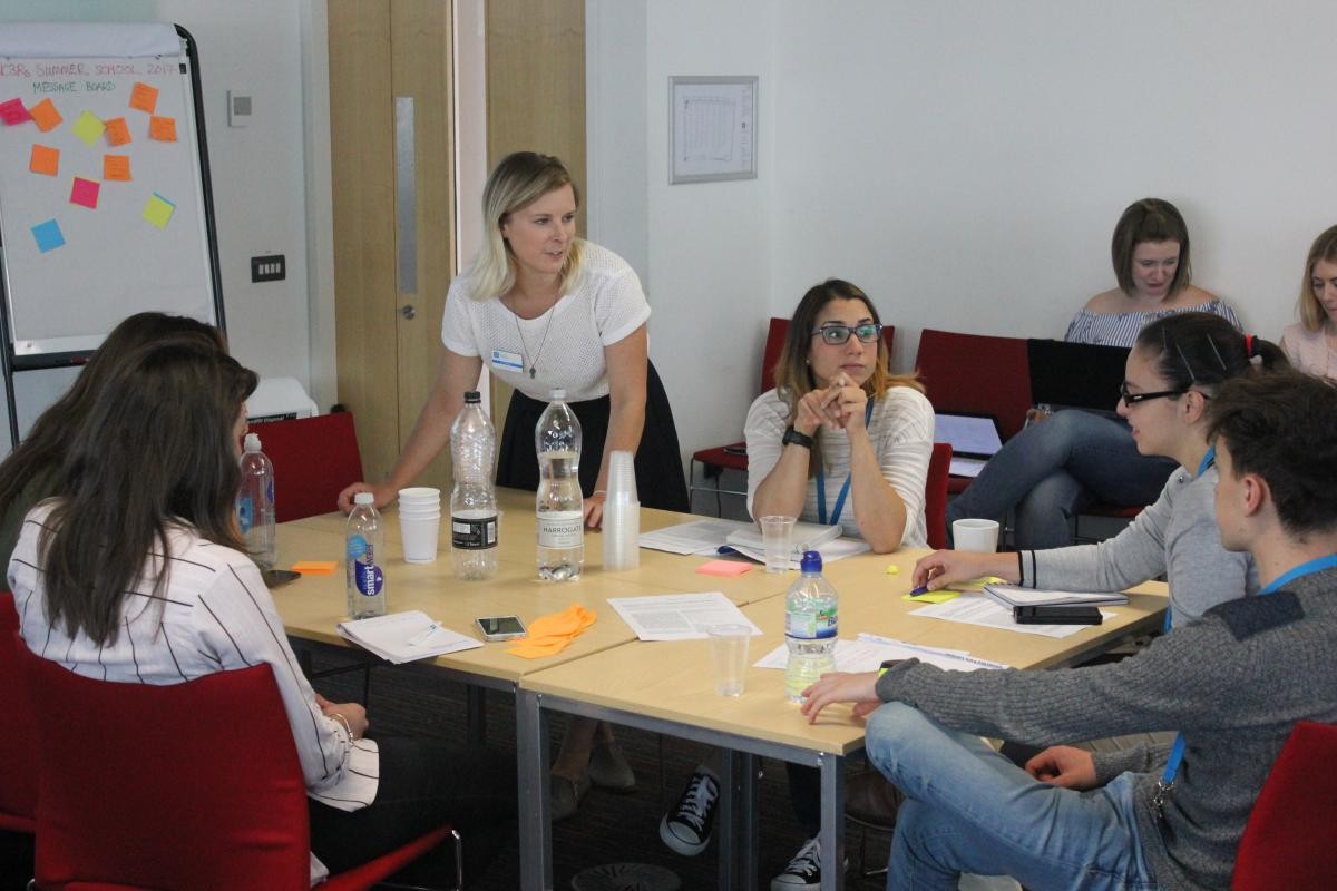 Students in a classroom sitting around a table team building