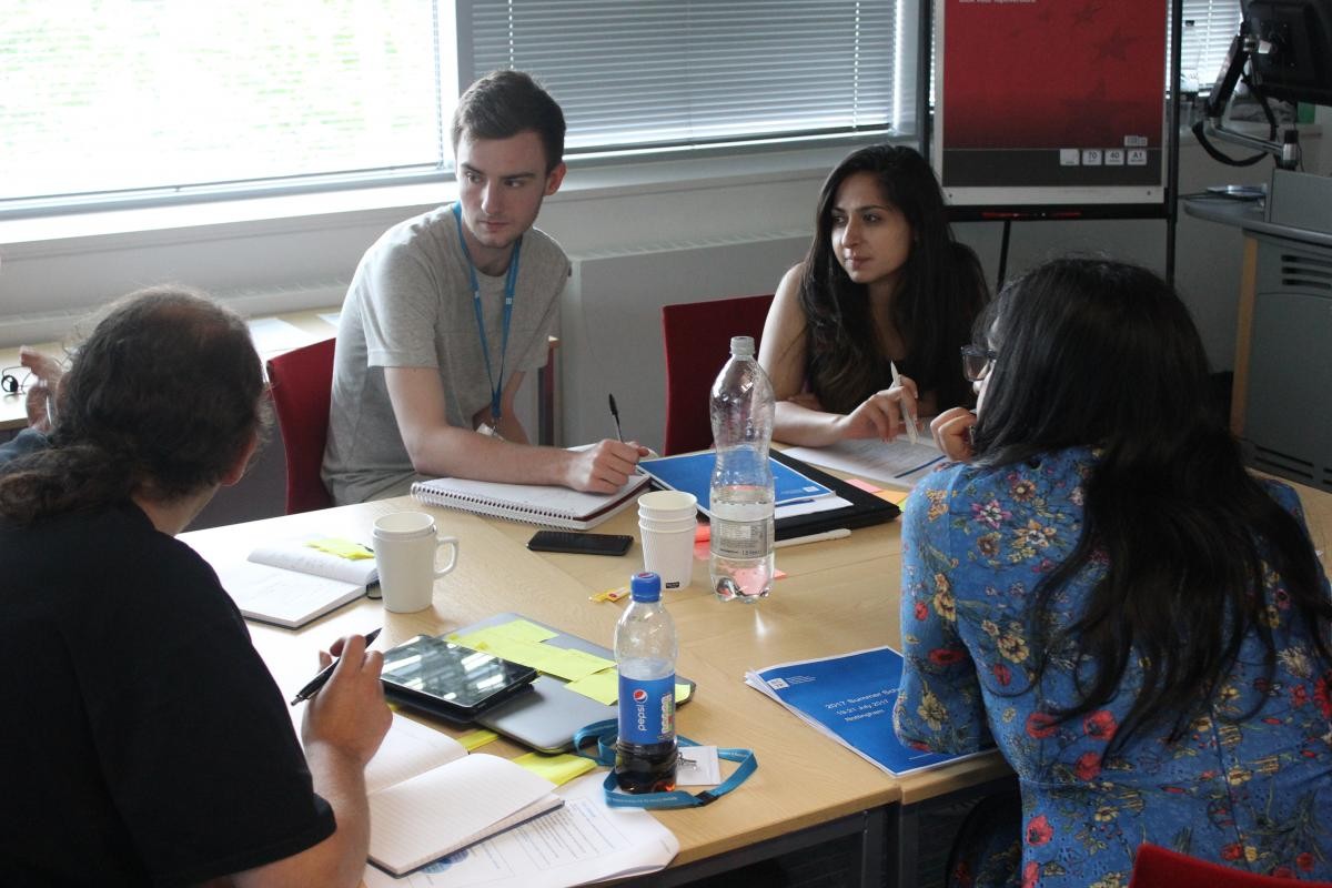 Students in a classroom sitting around a table in discussion 