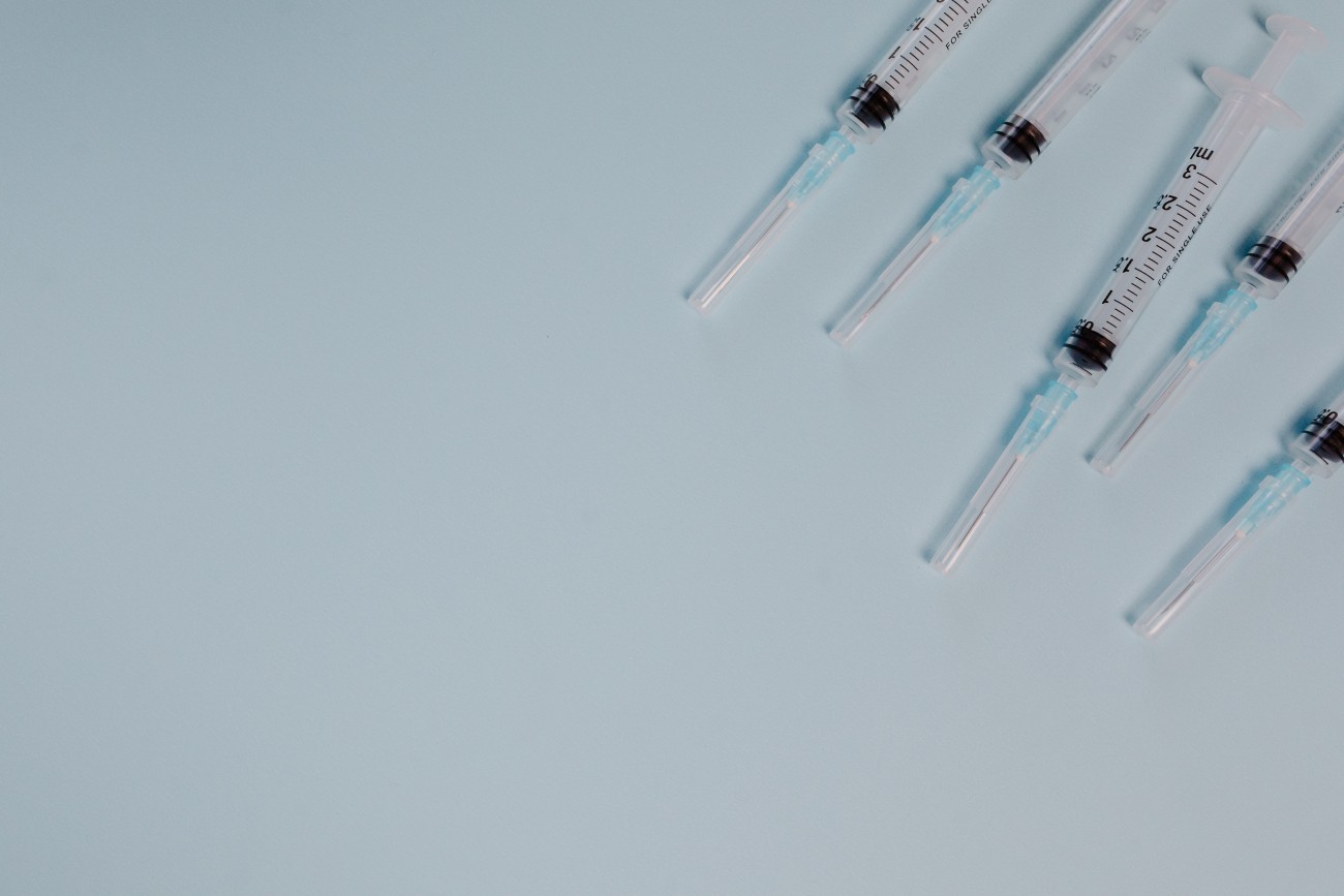 Five needles with empty syringes on a pale blue background