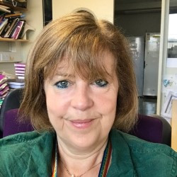 A portrait style photo of new Board member Cathy Abbott who has chin length light brown hair and is wearing a green shirt