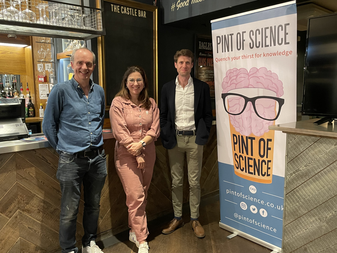 Dr Frank McCaughan and two other speakers stand by a Pint of Science banner