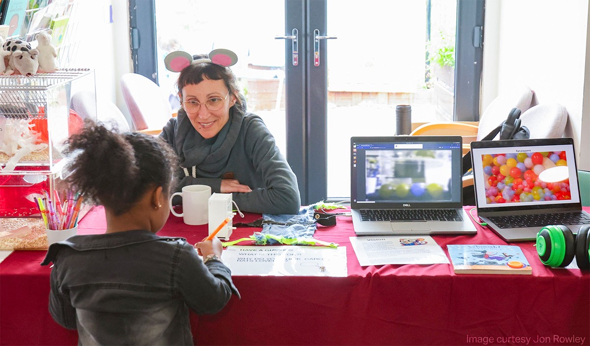A scientist speaking with a young child at a public engagement event.