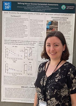 A smiling woman standing next to a scientific poster