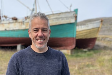 Dr Matthew Witt with two boats on grass in the background