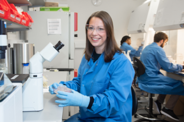 Dr Rachel Tanner sitting down beside a microscope