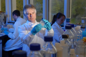 Professor Richard Titball sitting down observing a specimen