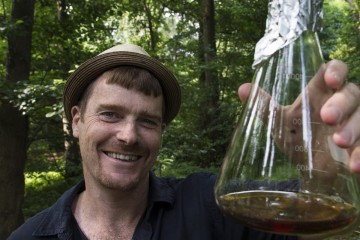 Professor Robin Williams holding up a beaker in woodlands