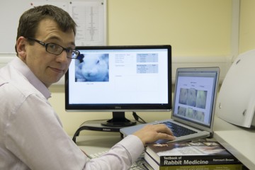 Side shot of Dr Matt Leach on a laptop and a monitor beside it