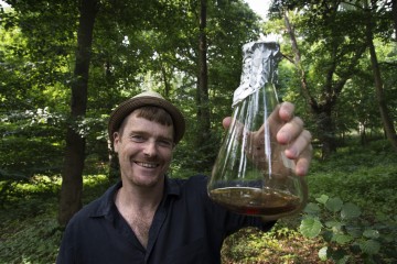 Portrait of Professor Robin Williams holding a conical flask of Dictyostelium